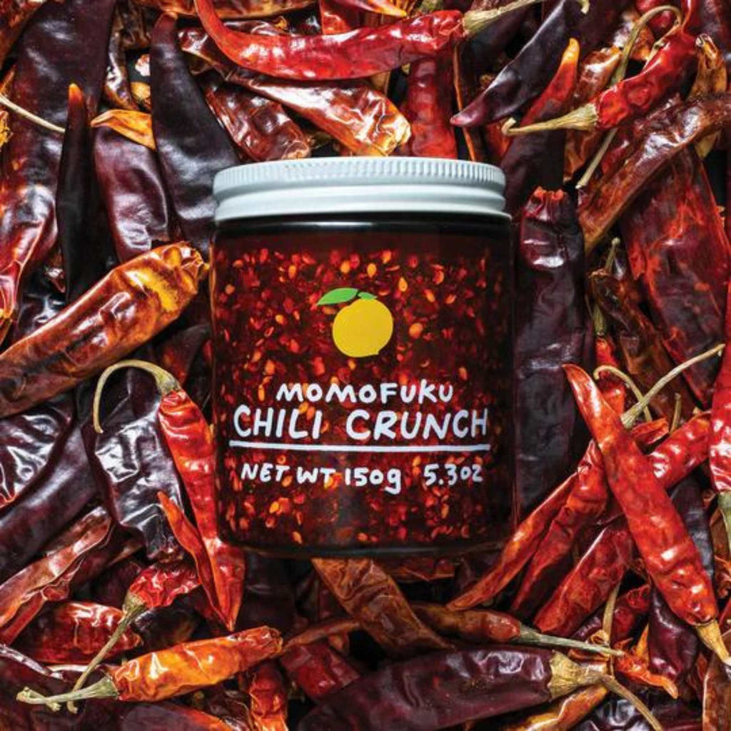 Momofuku chili crunch 5.3 oz. against background of chili peppers