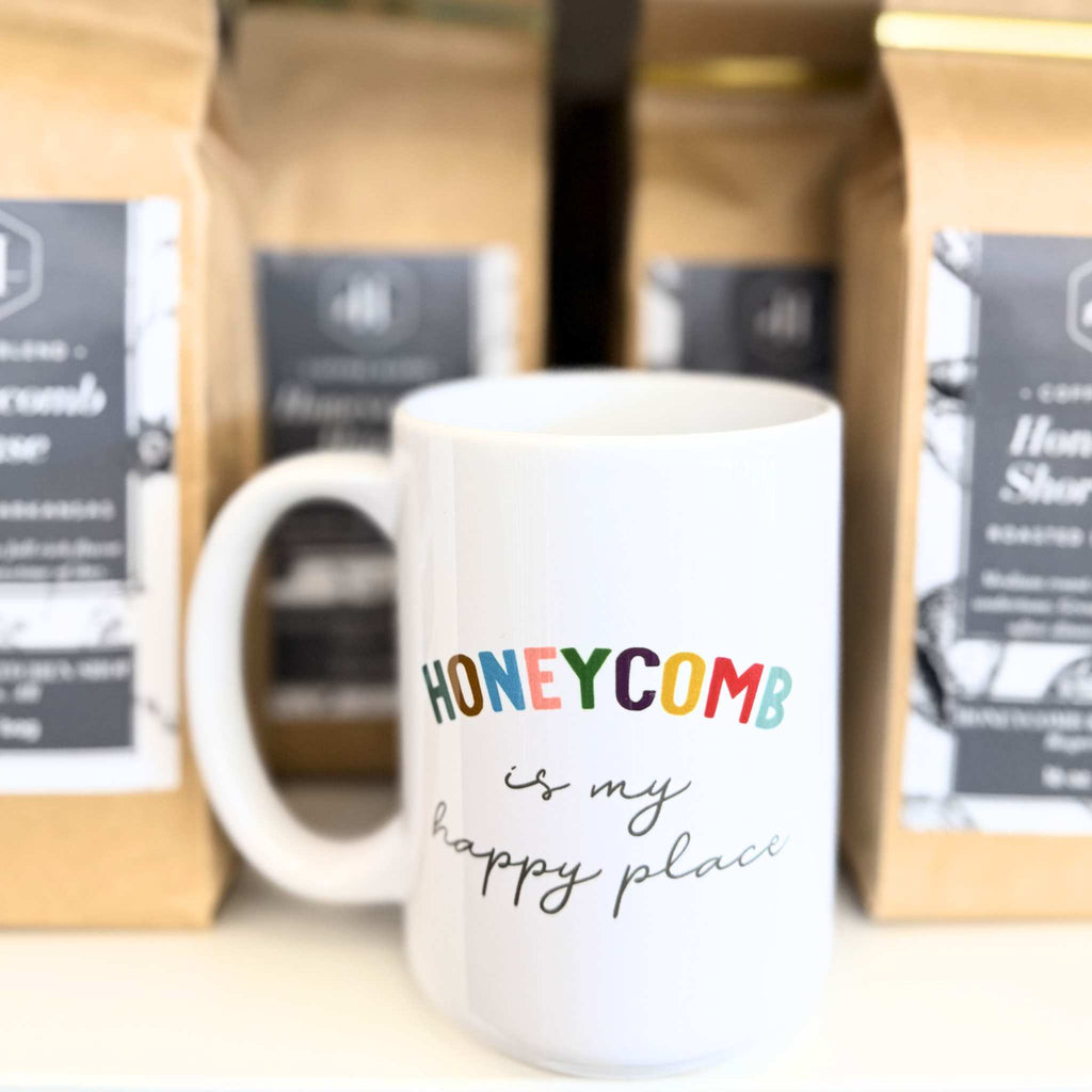 Coffee mug that says honeycomb is my happy place placed in front of coffee bags