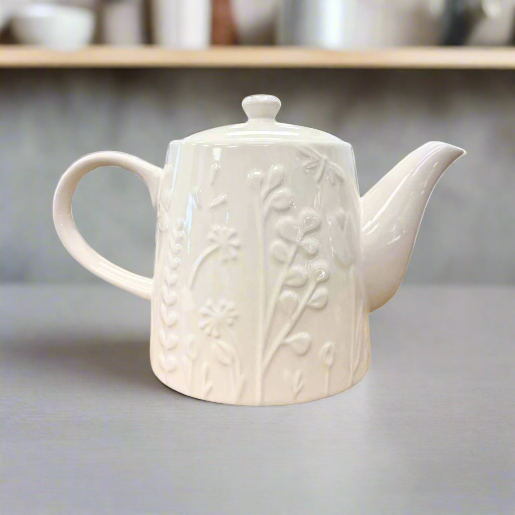 tea pot by mason cash in a kitchen with shelving in the background toward the top with things on the shelf.